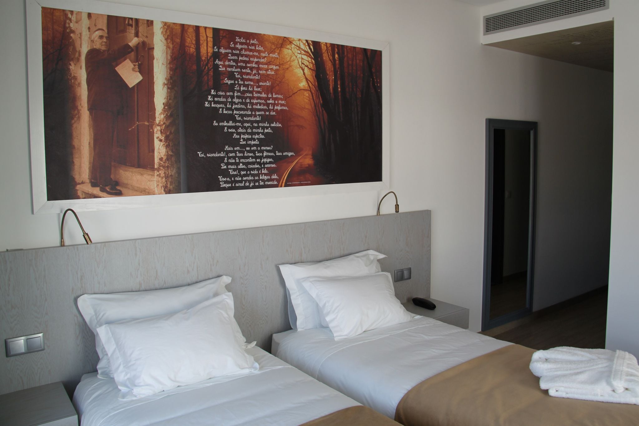 Habitación de hotel con dos camas, una obra de arte grande colgada en la pared y una puerta visible que conduce a otra habitación.