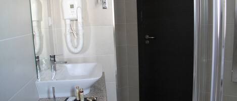 A modern bathroom with a white sink, a handheld showerhead, and a towel rack.
