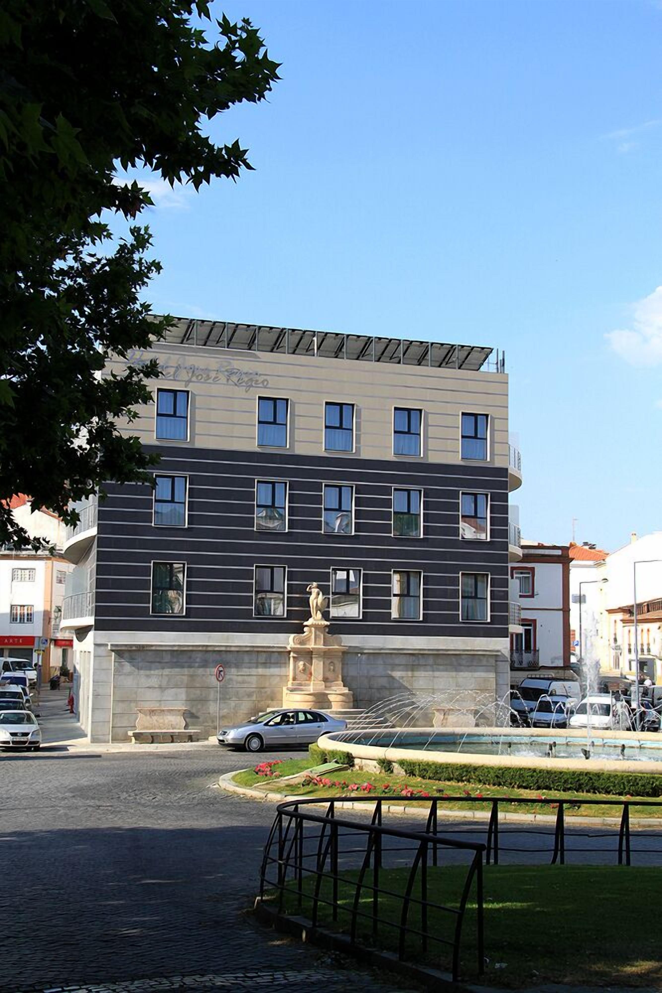 Un edificio moderno con varios pisos, un patio central con una fuente y una estatua.