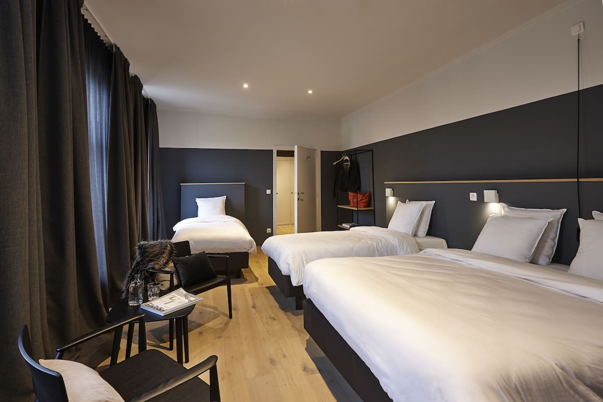 A hotel room with two beds, a desk, and a chair.