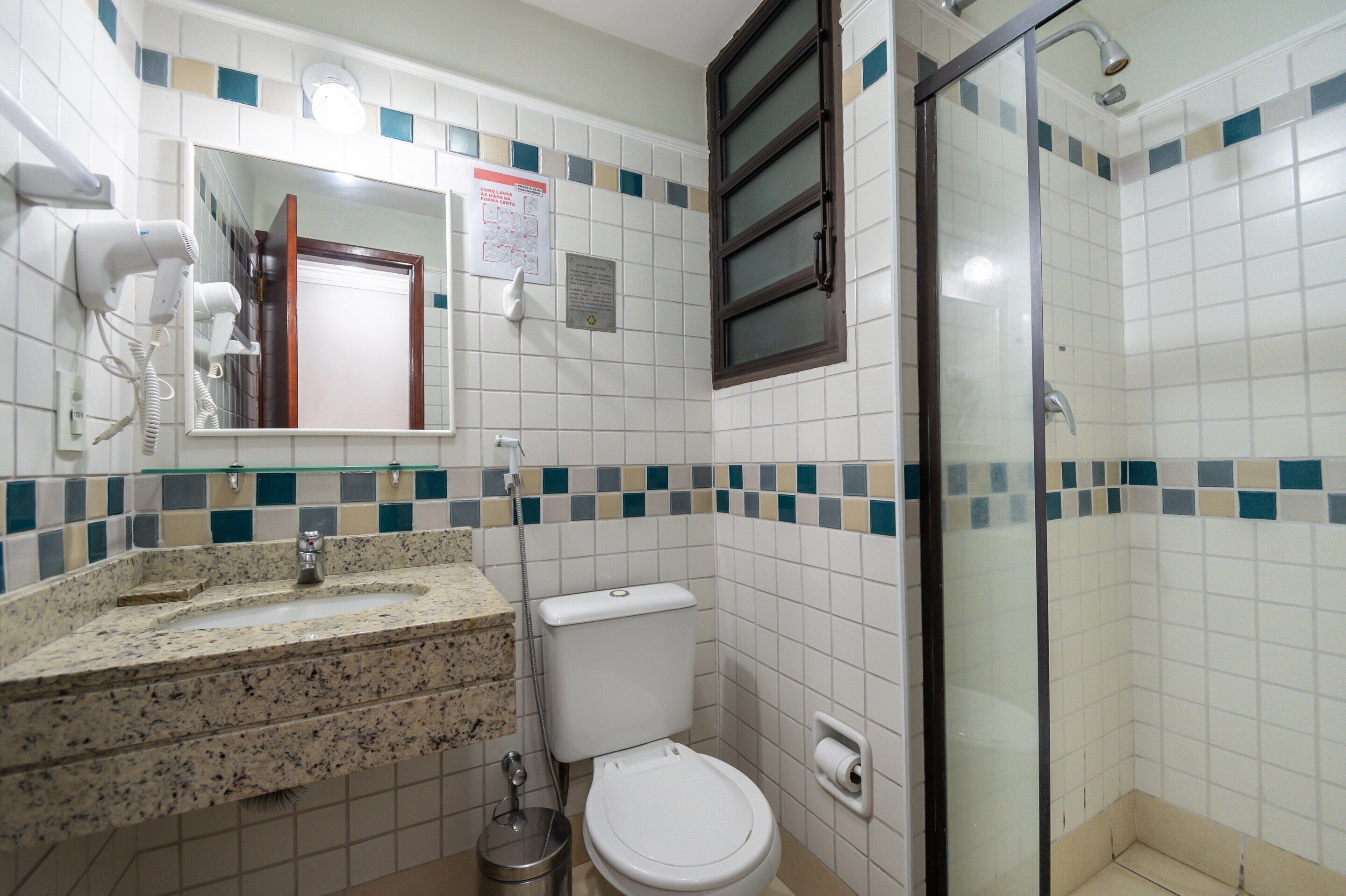 Een badkamer met een wastafel, toilet en een douchecabine met glazen wanden.