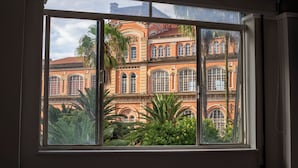 A window with a view of a historic building with multiple arches and large windows. - Rede Andrade Piratininga (São Paulo)