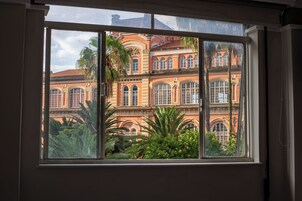 Una finestra che si affaccia su un edificio storico con numerose arcate e ampie finestre.