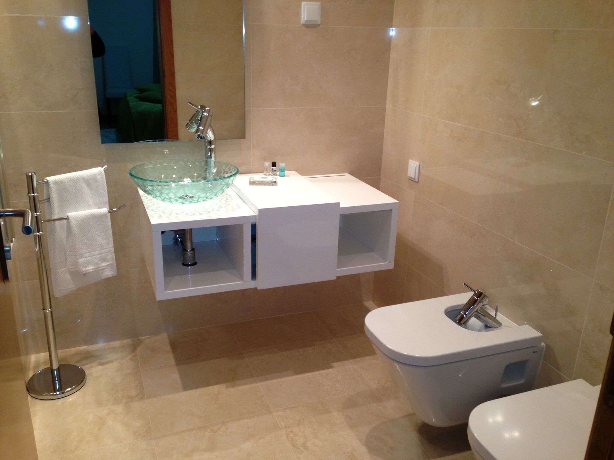 Un baño moderno con un lavabo de vidrio, un inodoro y un espejo sobre el lavabo.