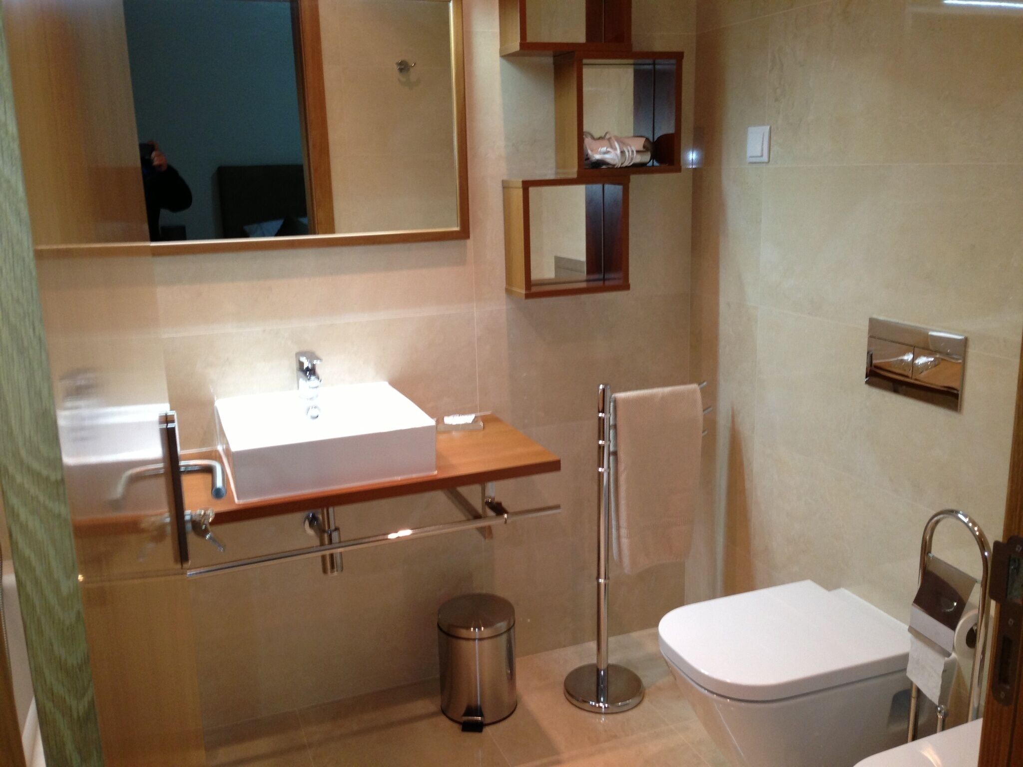 A modern bathroom with a sink, mirror, towel rack, toilet, and trash can.