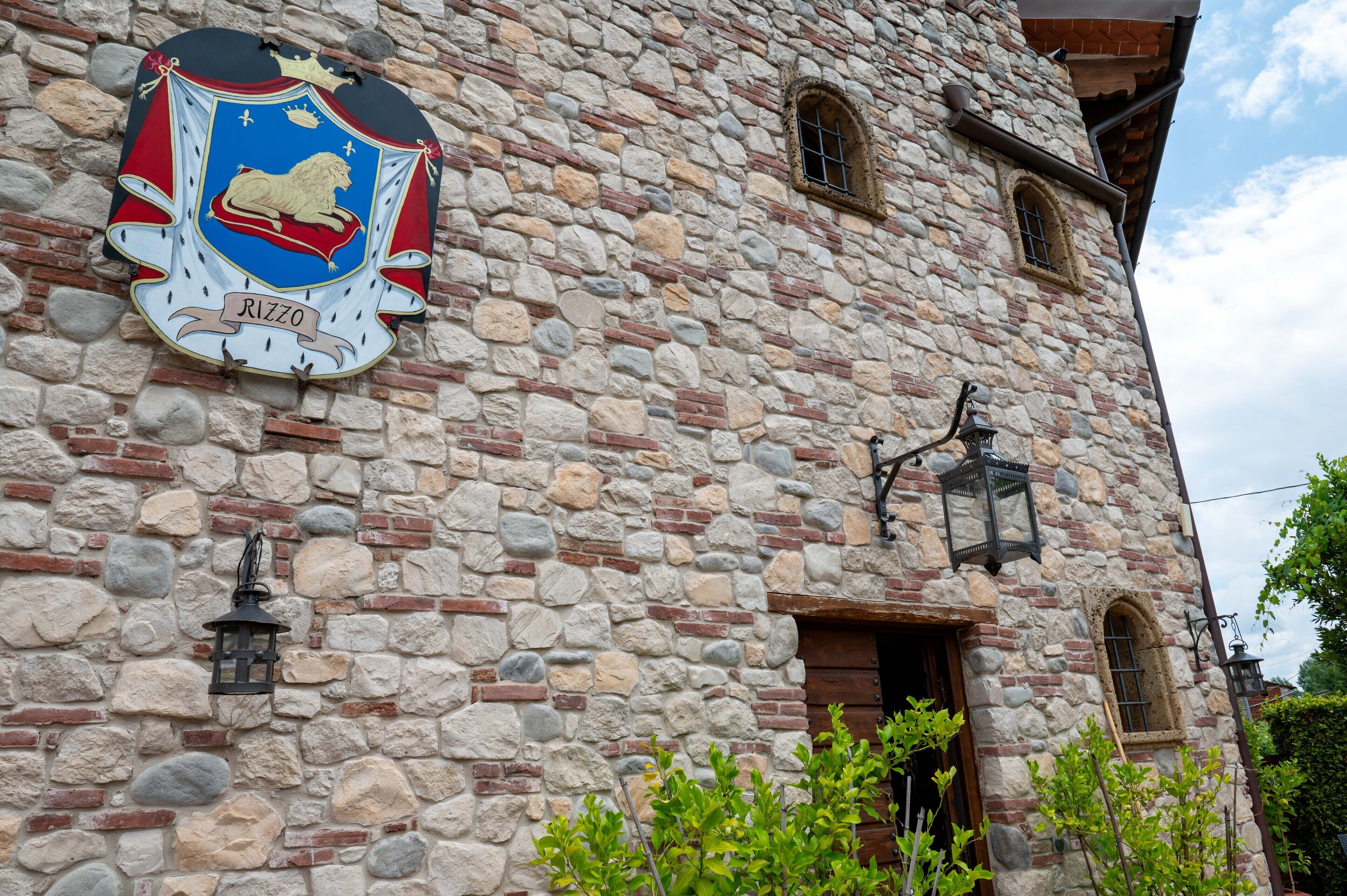 Un edificio de piedra con un escudo de armas y un farol.