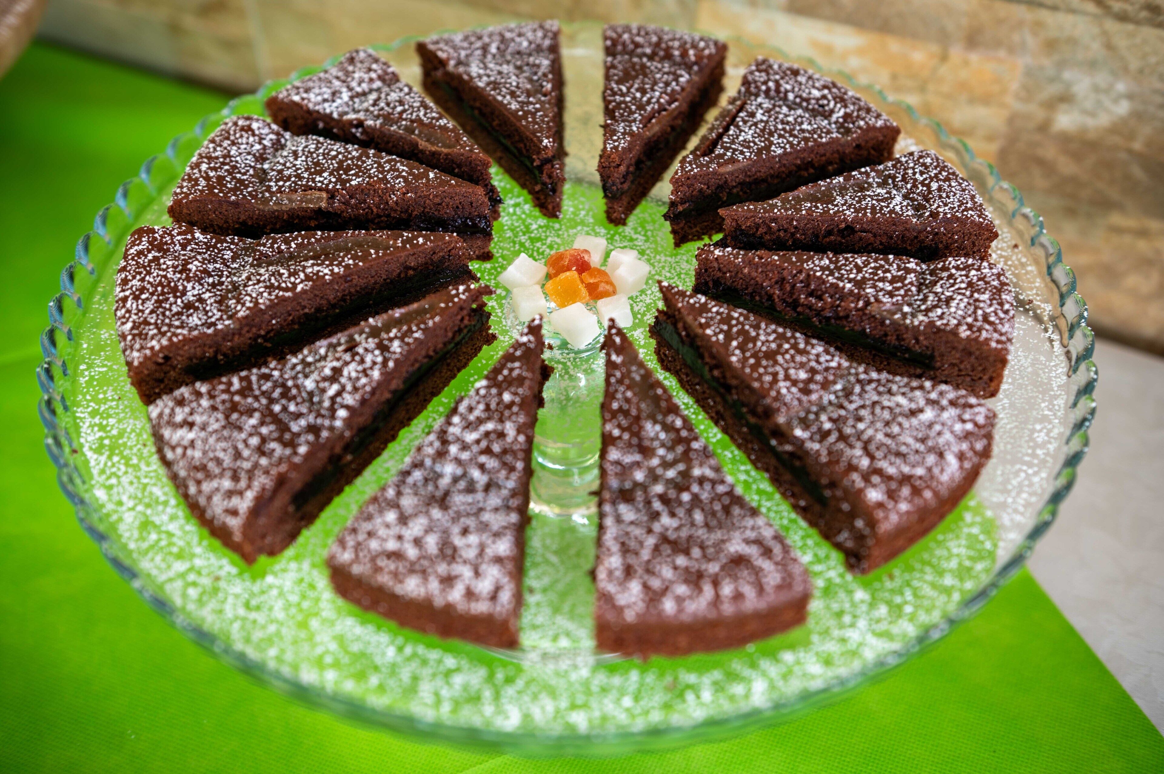 Un pastel redondo con porciones triangulares sobre un plato verde.