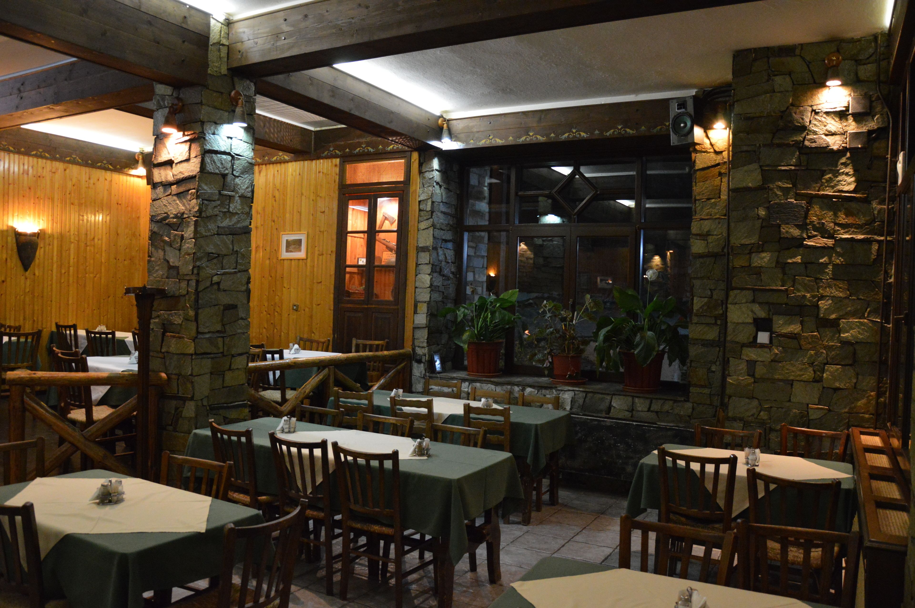 Un restaurante con paredes de madera y detalles de piedra, con mesas y sillas dispuestas para comer.