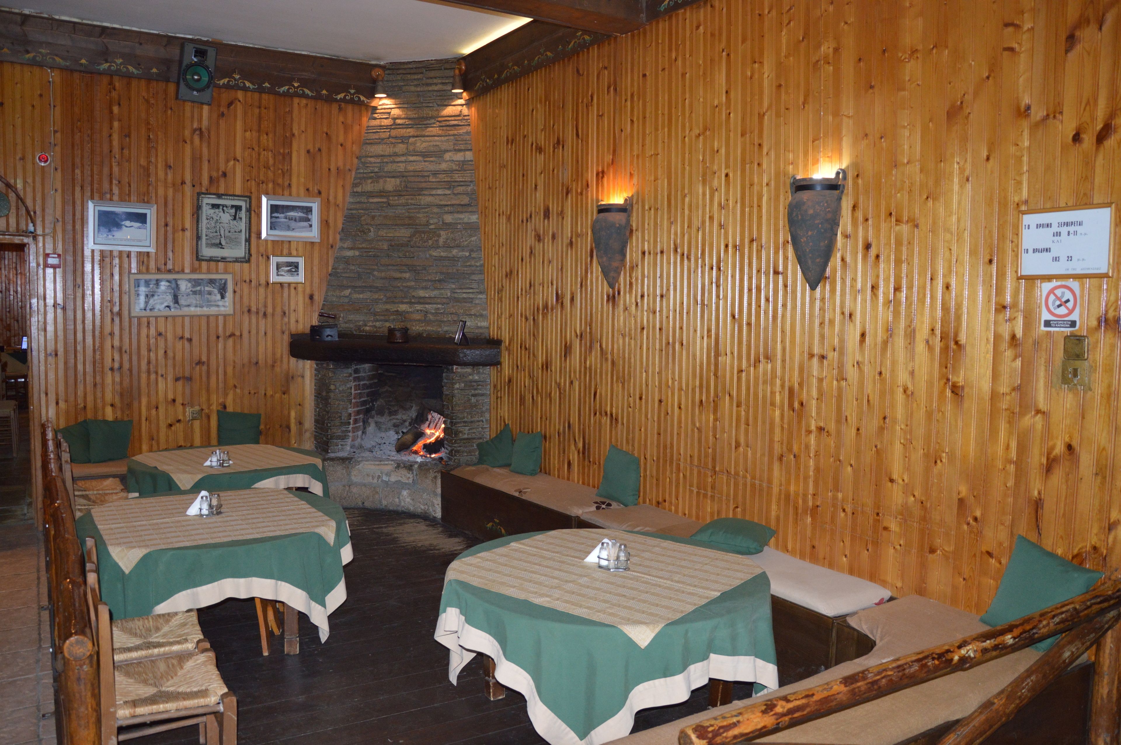 Ein gemütliches Restaurant mit Holzwänden, einem Steinofen und Tischen mit grünen Tischdecken.