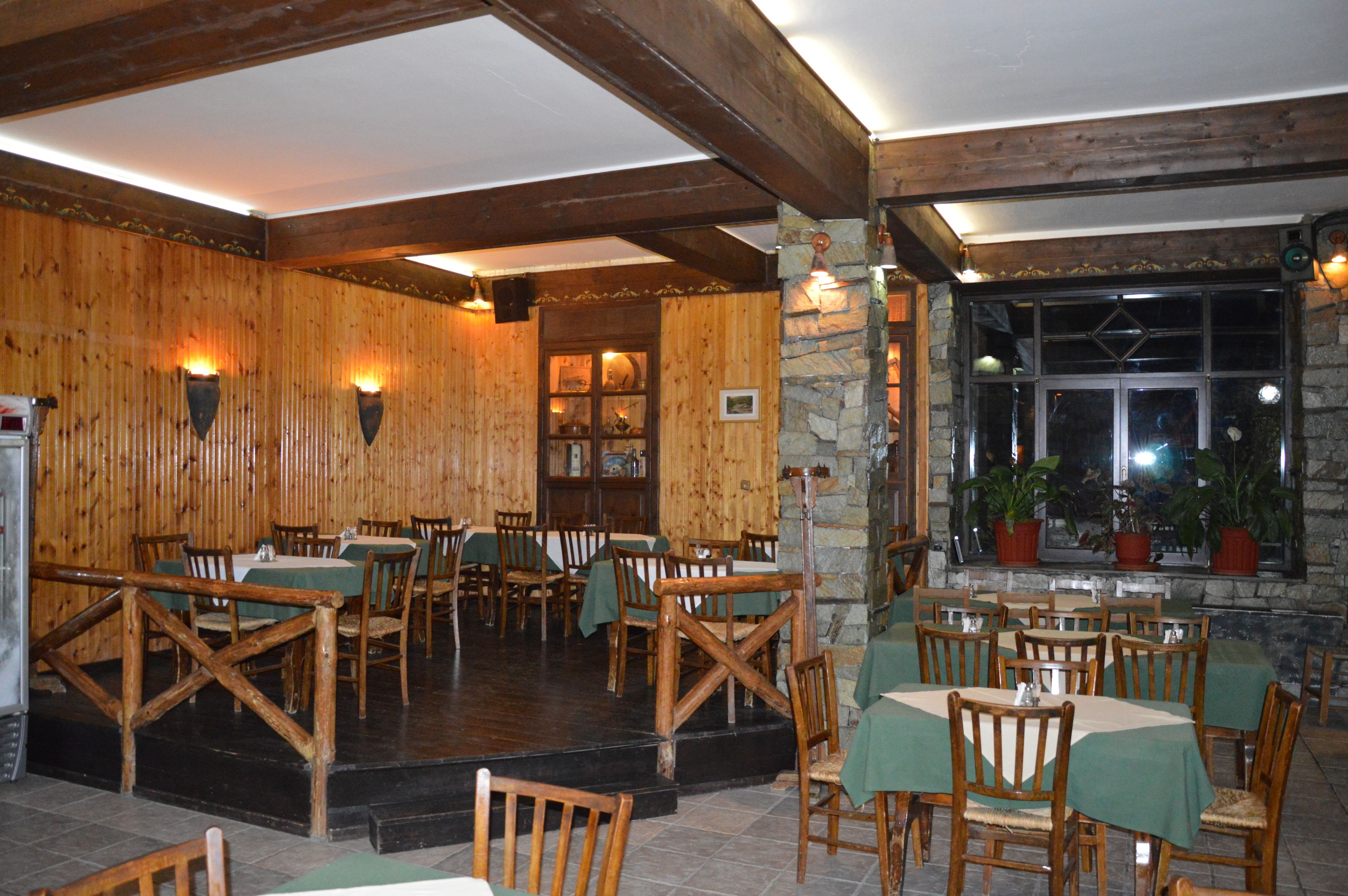 A restaurant with wooden walls and stone accents, featuring tables and chairs set for dining.