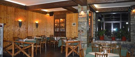 A restaurant with wooden walls and stone accents, featuring tables and chairs set for dining.