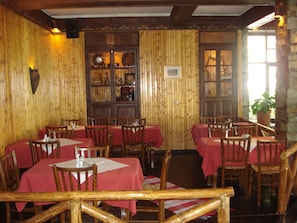 Ein Restaurant mit Holzwänden, roten Tischdecken und Holzhockern.