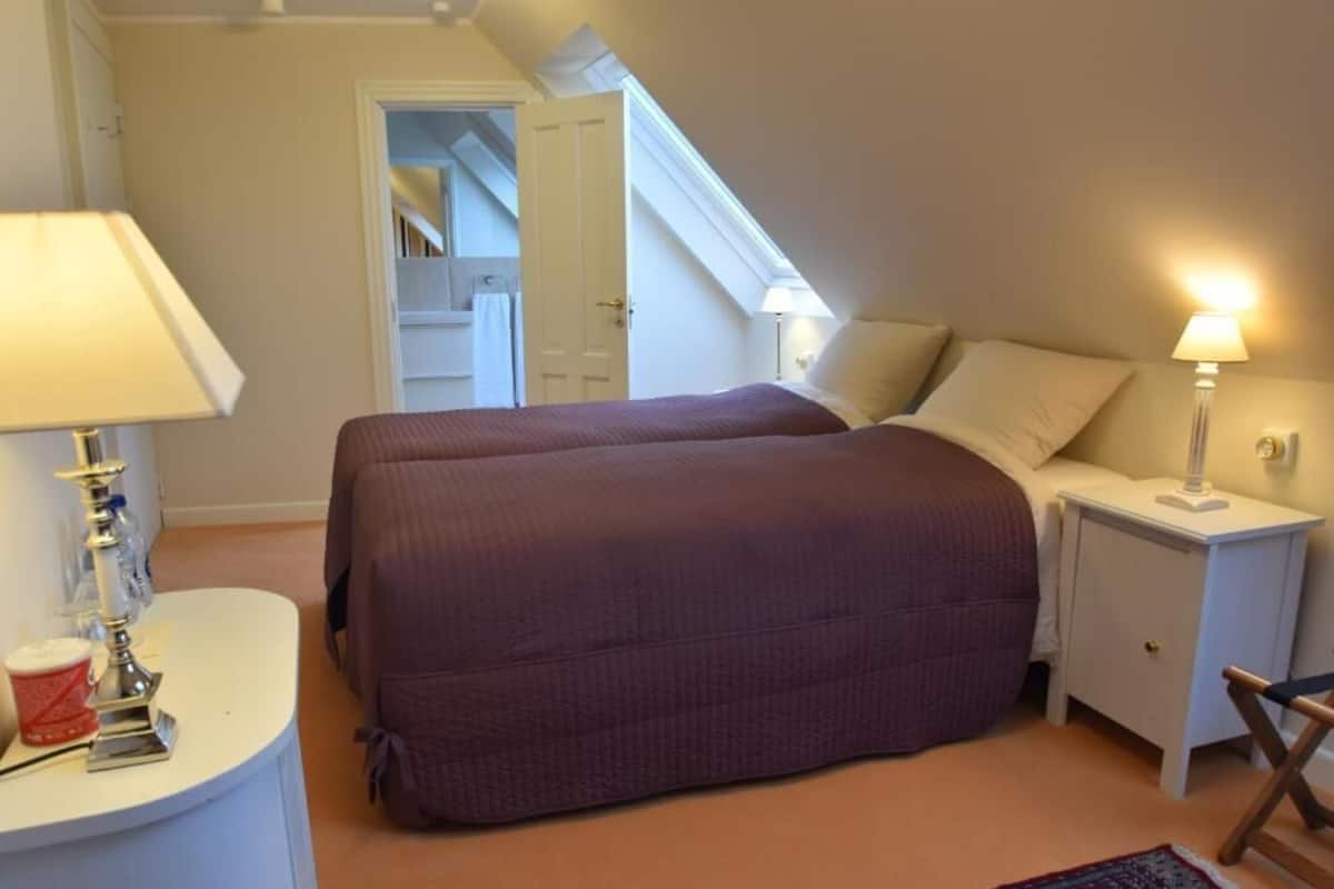 Une chambre avec deux lits, une table de chevet, une lampe et une petite table sur laquelle se trouvent une tasse et un narguilé.