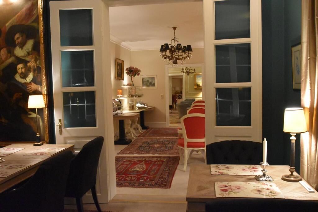 A dining area with a chandelier, a red and white striped chair, and a table set with a floral table runner.