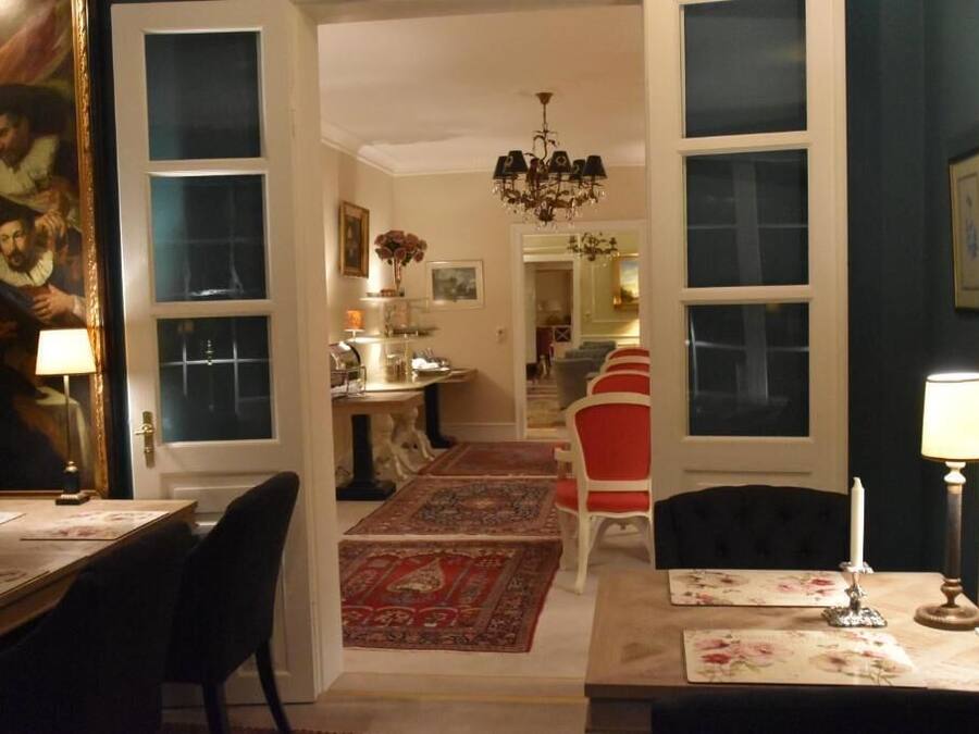 A dining area with a chandelier, a red and white striped chair, and a table set with a floral table runner.
