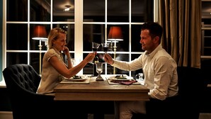 Una mesa de comedor con dos personas brindando con copas de vino.