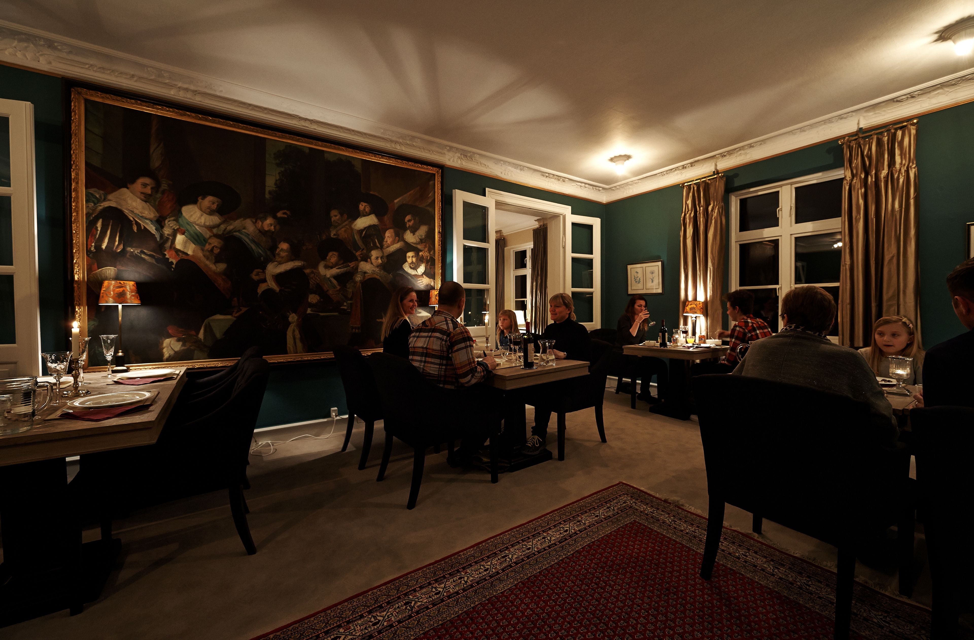A dining room with a large painting, multiple tables, and chairs.