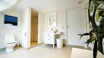 Un baño moderno con inodoro, lavamanos y ducha.