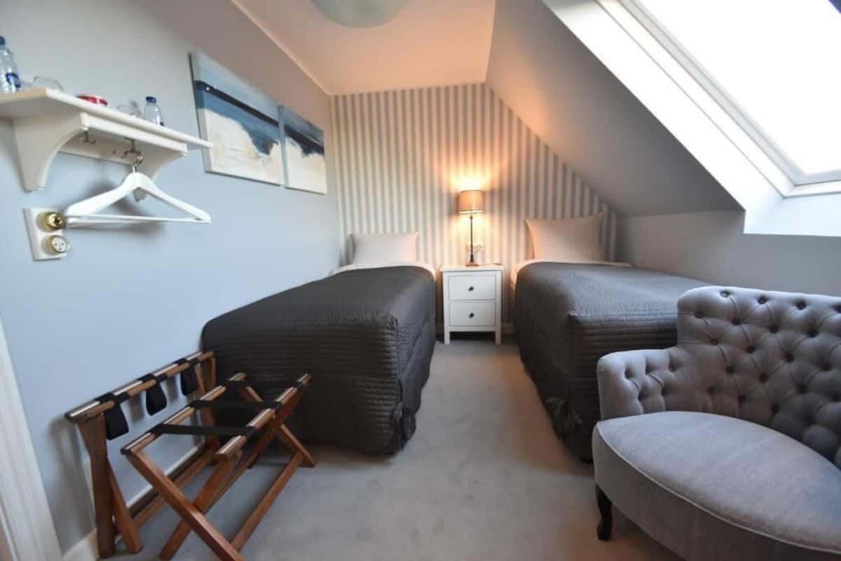 Une chambre avec deux lits, un fauteuil suspendu, un bureau et une lampe.