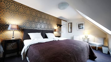 A bedroom with a large bed, two bedside tables with lamps, a chair, and a wall-mounted light fixture.