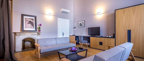 A modern living room with a sofa, a coffee table, a fireplace, a TV, and a wooden wardrobe.