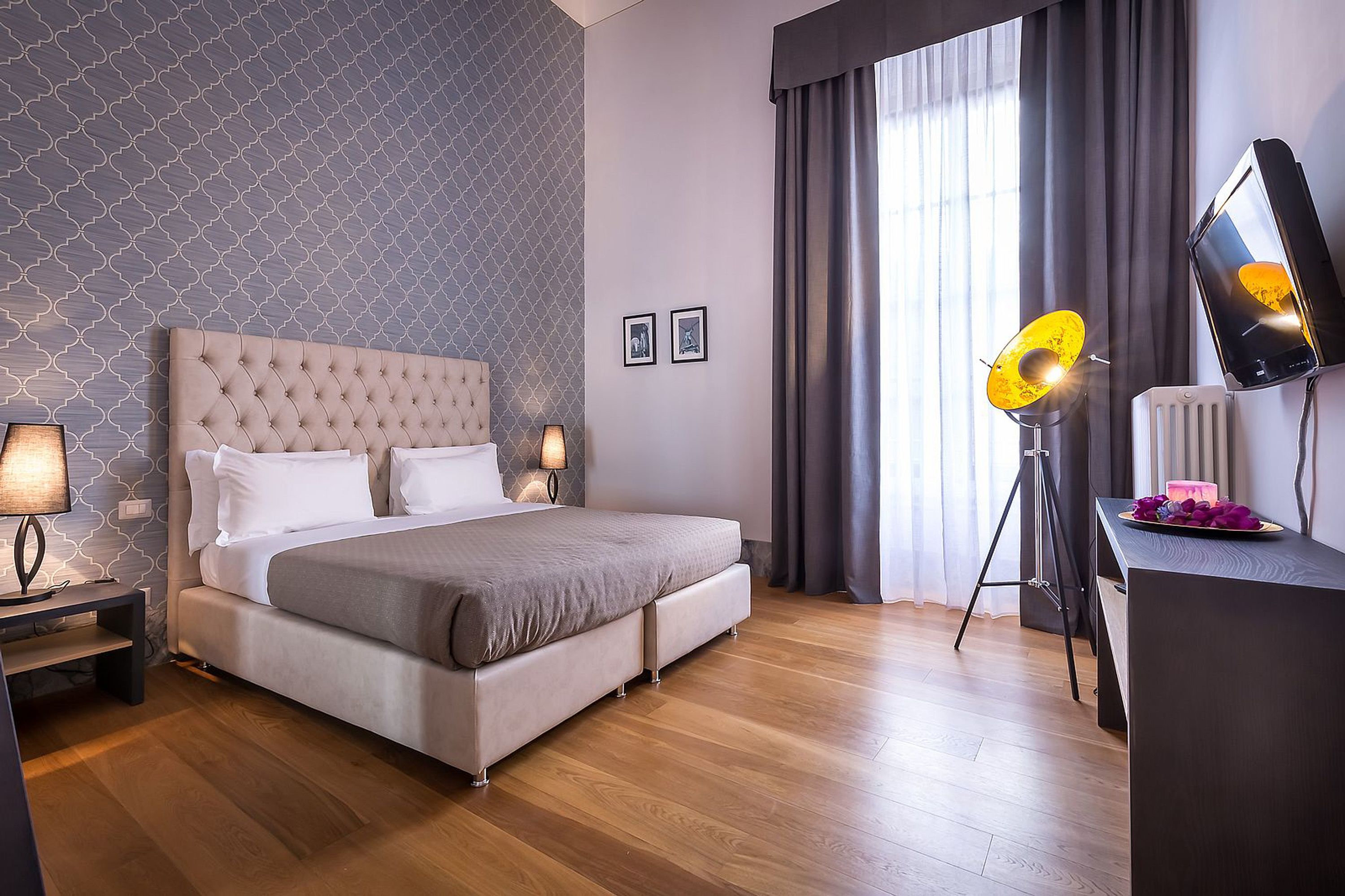 Un dormitorio moderno con una tapizada, una cama grande, un escritorio con lámpara y vistas al exterior.
