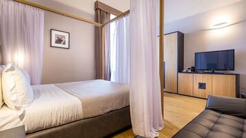 A modern hotel room with a bed, a sofa, a TV, and a wooden cabinet.