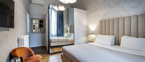 A modern hotel room with a large bed, a seating area with a coffee machine, and a view through a glass door.