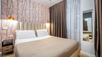 Habitación de hotel con una cama grande, una mesita de noche, un espejo y vistas a un balcón.