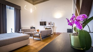 A modern living room with a sofa, a coffee table, and a bed. There is a potted orchid on a table. - La Torre Del Cestello (Florence)