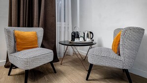 Two patterned chairs with orange cushions, a small round table with a kettle and cups, and a view of a building through a window with curtains. - La Torre Del Cestello (Florence)