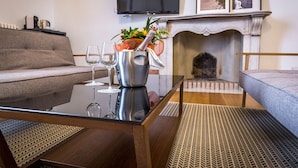 A modern living room with a sofa, a coffee table with a bottle of champagne, and a fireplace. - La Torre Del Cestello (Florence)
