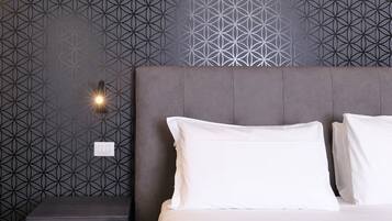 Un dormitorio moderno con papel tapiz de diseño geométrico, cabecera capitonada y mesita de noche con lámpara.