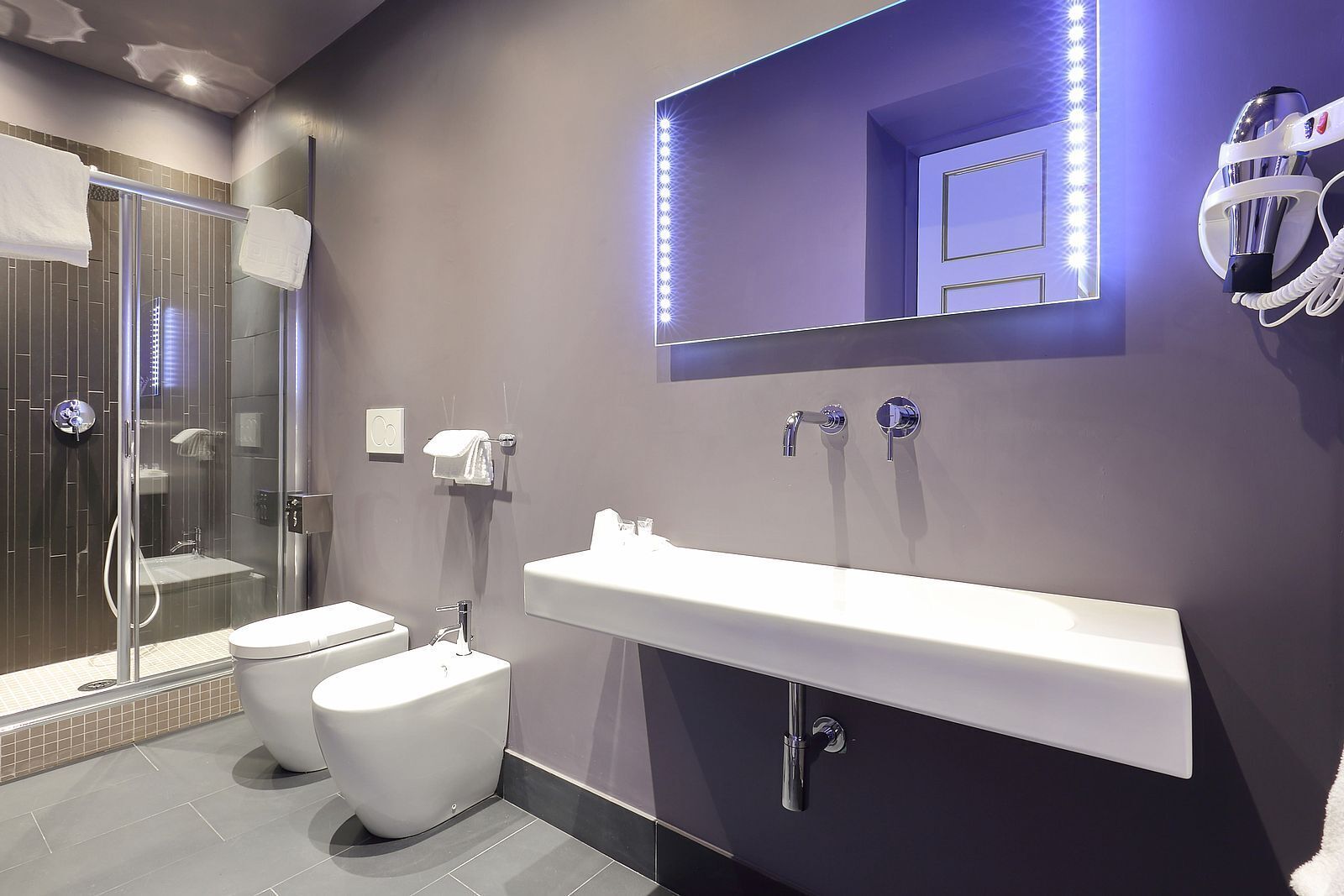 A modern bathroom with a glass-enclosed shower, a white toilet, and a vanity with a mirror.