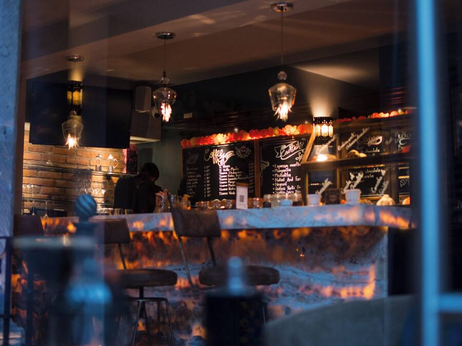A bar area with a brick wall, hanging lights, and a menu board.
