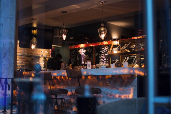 Zona de bar con pared de ladrillo, luces colgantes y una pizarra de menú.
