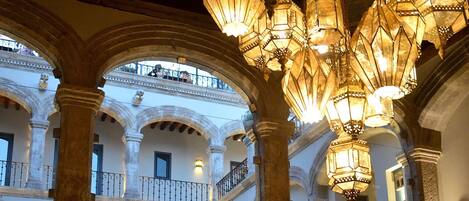 An interior courtyard with ornate columns, hanging lanterns, and a checkered floor.