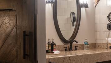 A bathroom with a large mirror, a towel rack, and a sink with toiletries.