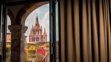 A view of a historic cathedral through an open doorway, with a balcony and outdoor seating area visible.