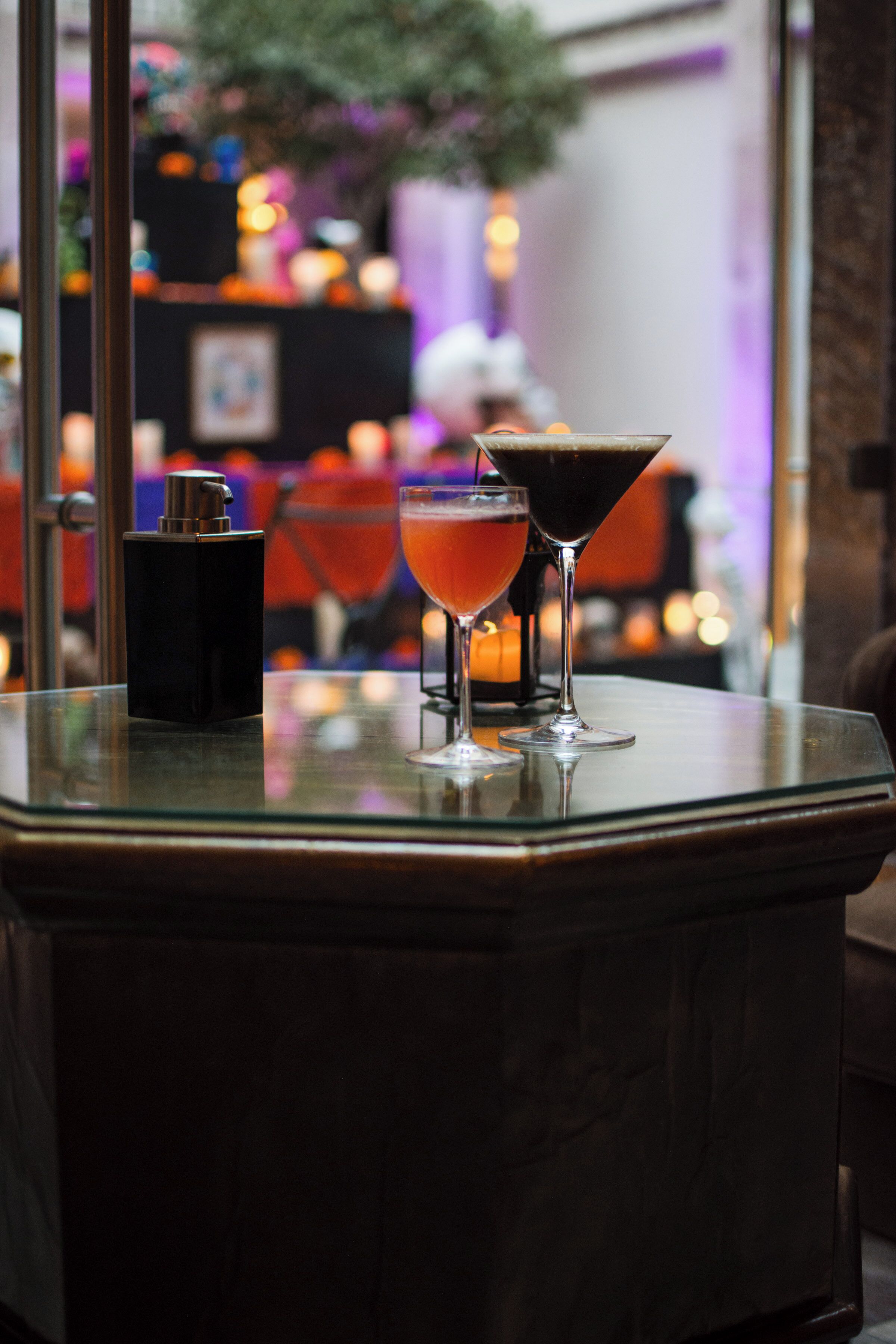 A bar area with two glasses of drink on a glass table.