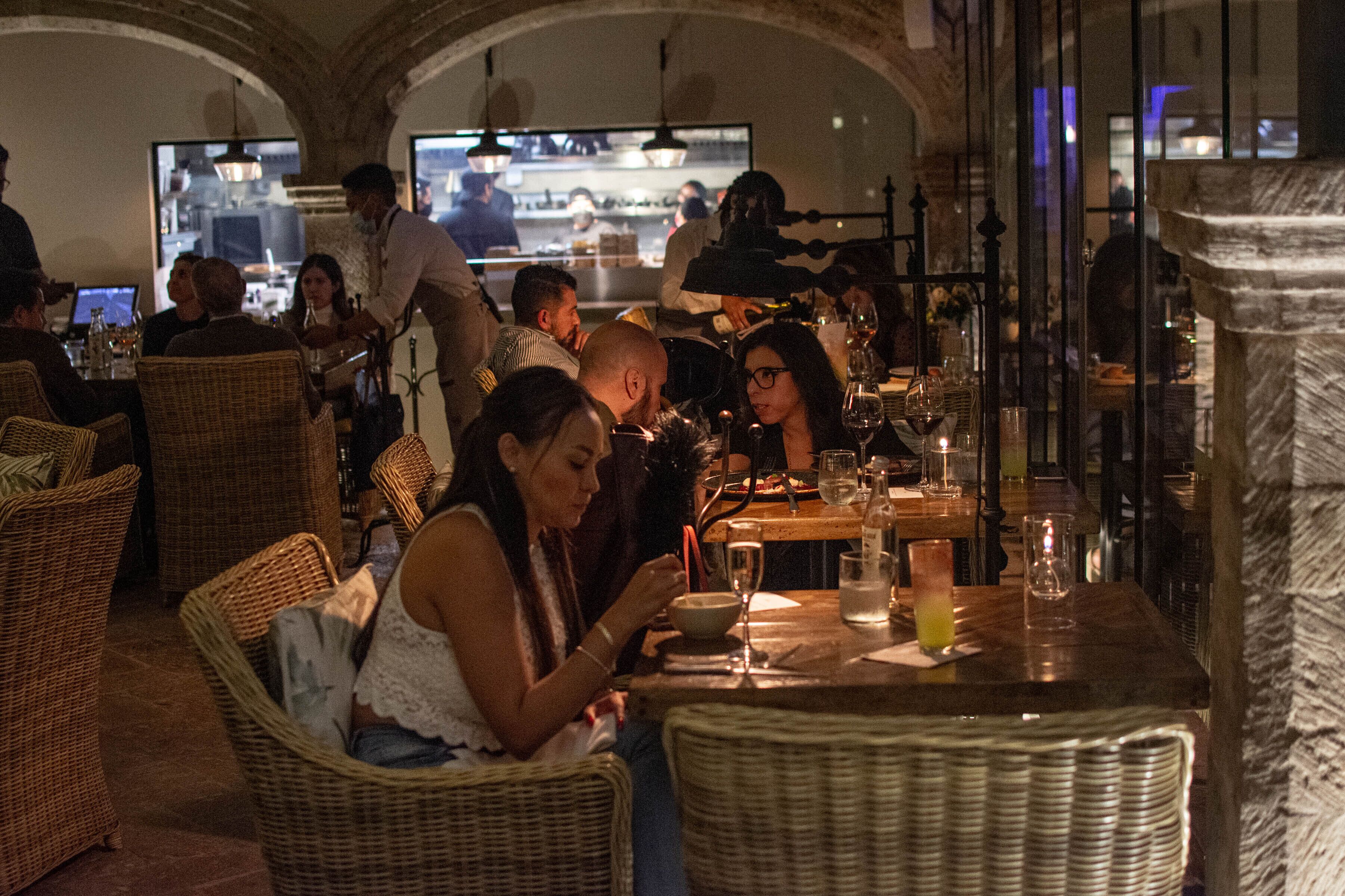Un restaurante con mobiliario de mimbre y una pared de piedra.