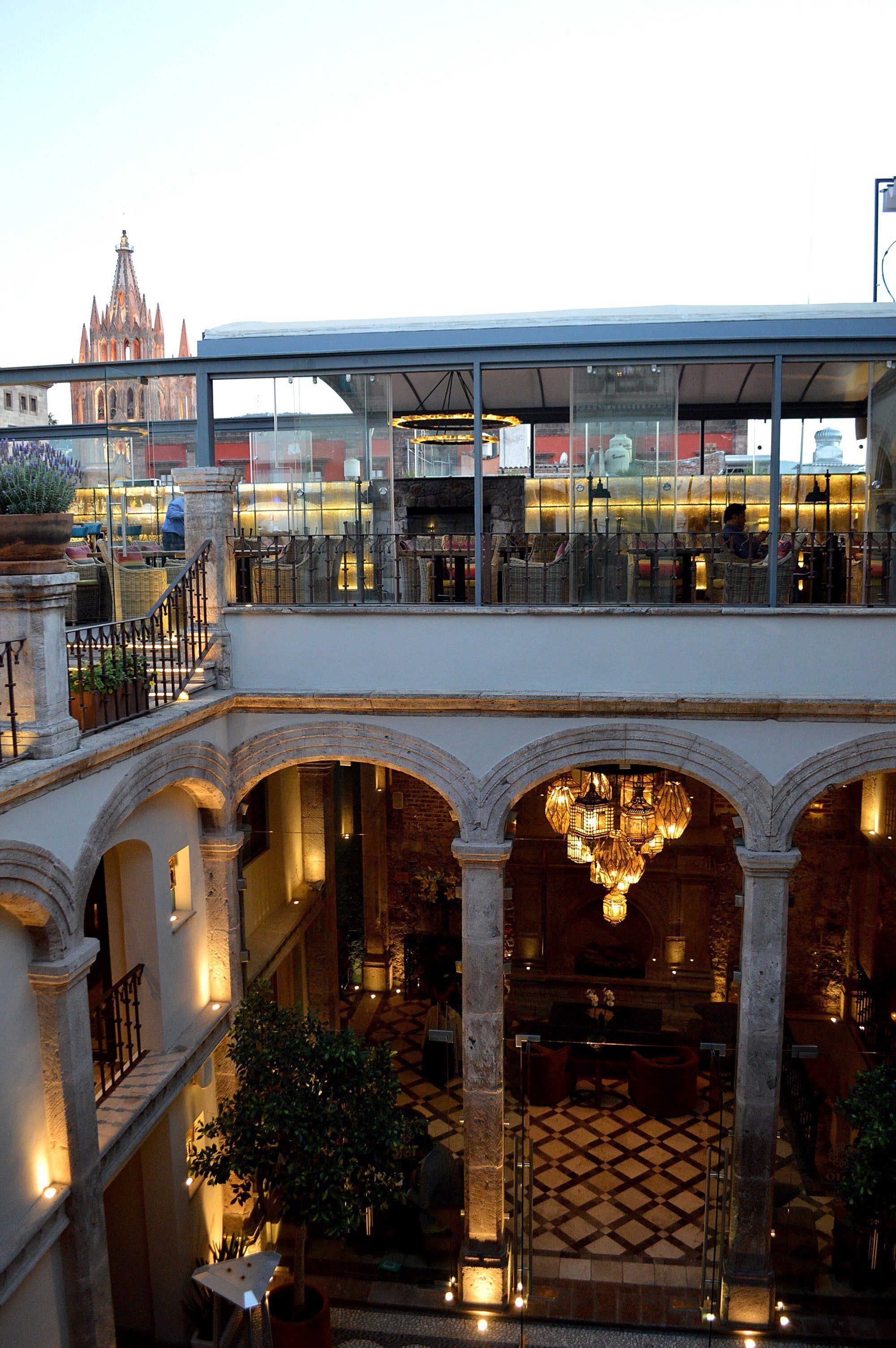 Un hôtel doté d’un étage supérieur avec un toit en verre et d’un étage inférieur avec des arcades et un lustre.