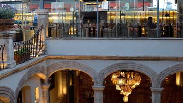 Un hôtel doté d’un étage supérieur avec un toit en verre et d’un étage inférieur avec des arcades et un lustre.