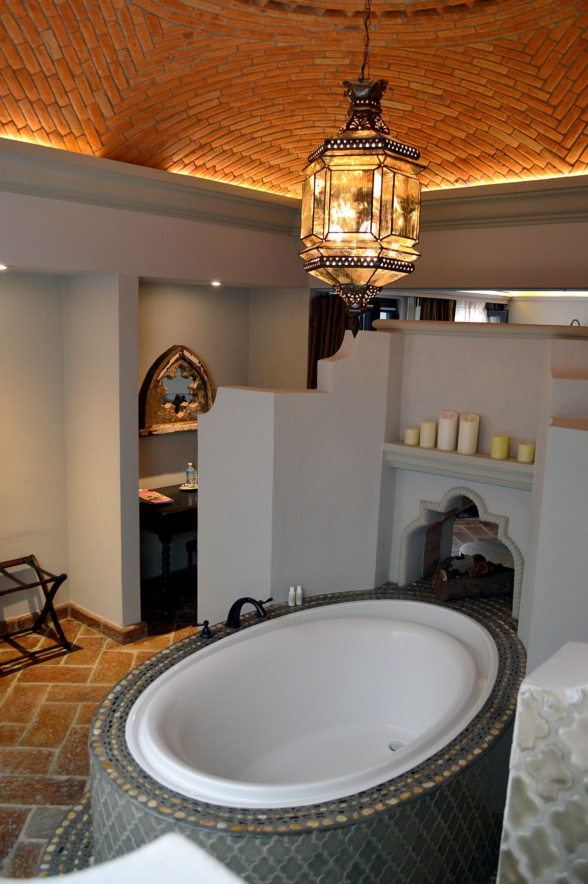 A bathroom with a large bathtub, a wooden chair, a mirror, and a hanging lantern.
