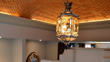 A bathroom with a large bathtub, a wooden chair, a mirror, and a hanging lantern.