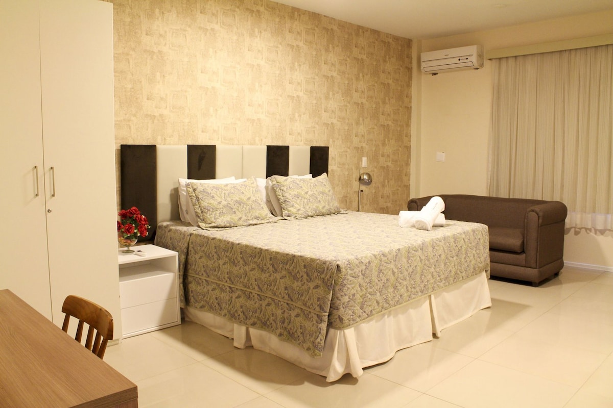 A hotel room with a bed, a sofa, a desk, and a chair.
