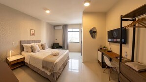 A modern hotel room with a bed, desk, chair, and a TV mounted on the wall. - San Phillip Flat Hotel (Fortaleza)