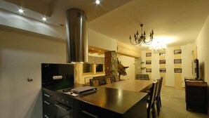 A modern kitchen with a central island, built-in oven, and a chandelier.