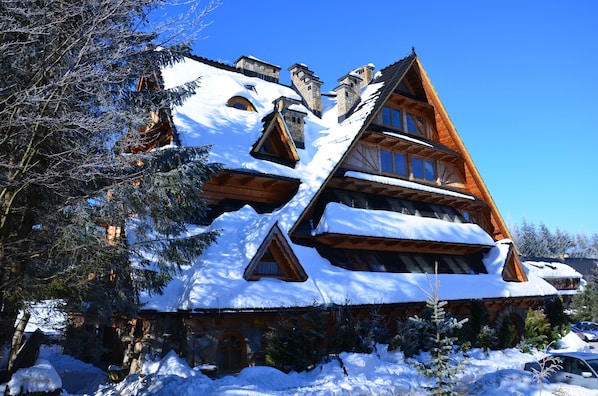 A multi-story log cabin with snow-covered roofs and a steeply pitched roof.