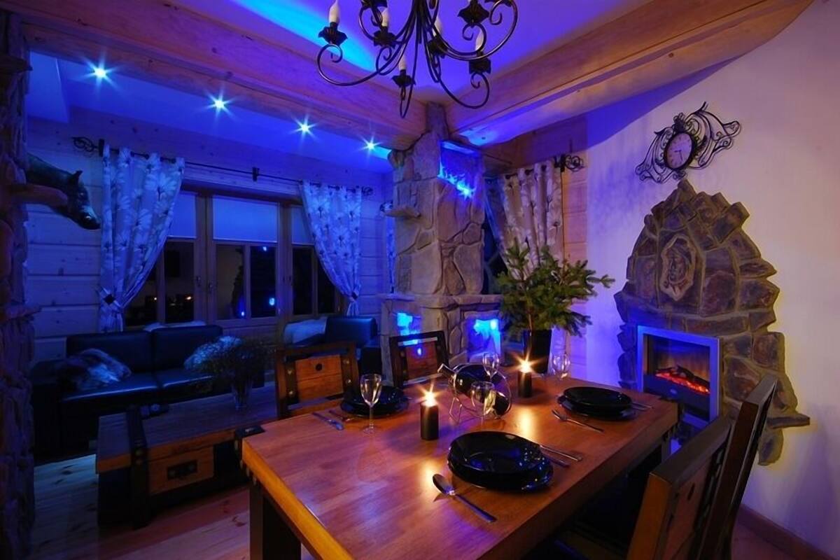 Ein gemütlicher Essbereich mit einem Holztisch für zwei Personen, einem Steinkamin und einer Chandelier.